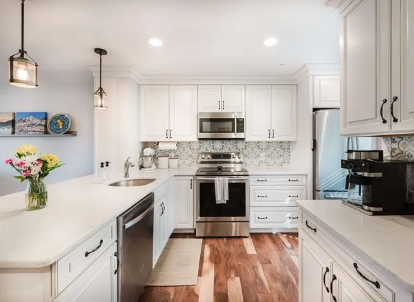a kitchen with granite countertop white cabinets and stainless steel appliances