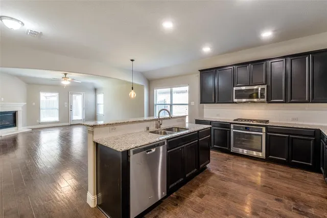 a kitchen with stainless steel appliances granite countertop a stove a sink and a microwave