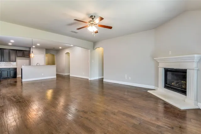 an empty room with a fireplace and kitchen view