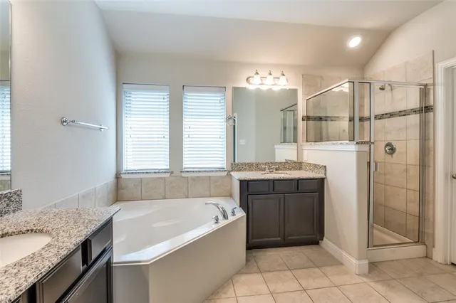 a bathroom with a granite countertop tub sink shower and mirror