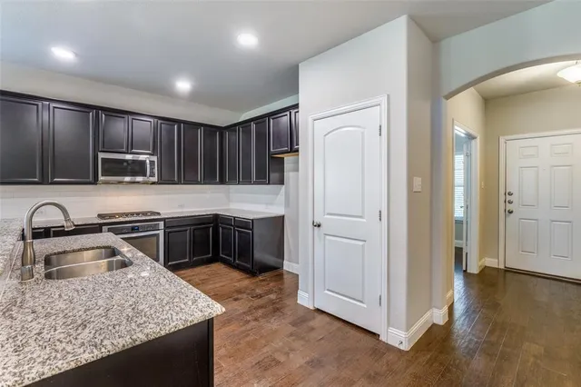 a kitchen with kitchen island granite countertop stainless steel appliances sink stove microwave and cabinets