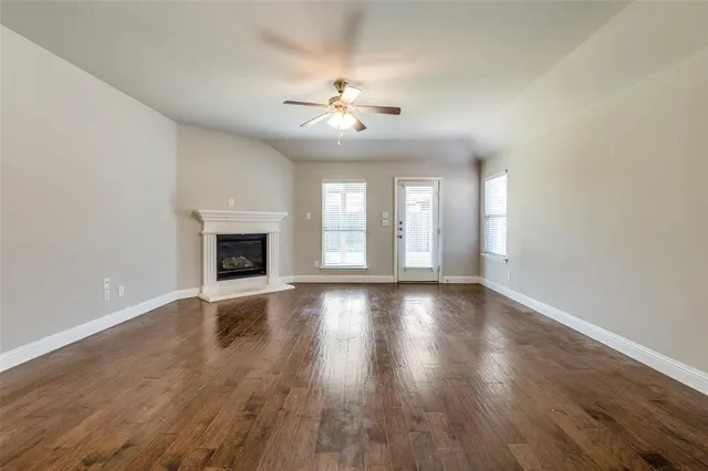 a view of an empty room with wooden floor and a fireplace