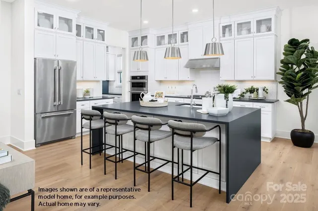 a kitchen with stainless steel appliances kitchen island granite countertop a dining table chairs and a refrigerator