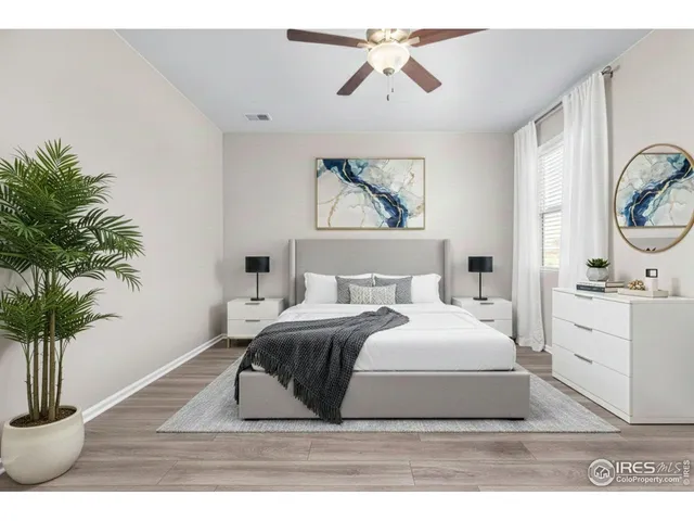 a bedroom with a large bed wooden floor and potted plant