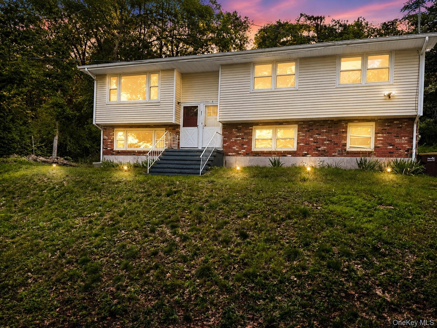Split-level residence featuring a brick and siding exterior, multiple windows, and exterior steps with handrails