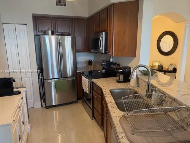 a kitchen with stainless steel appliances granite countertop a sink a refrigerator and a stove