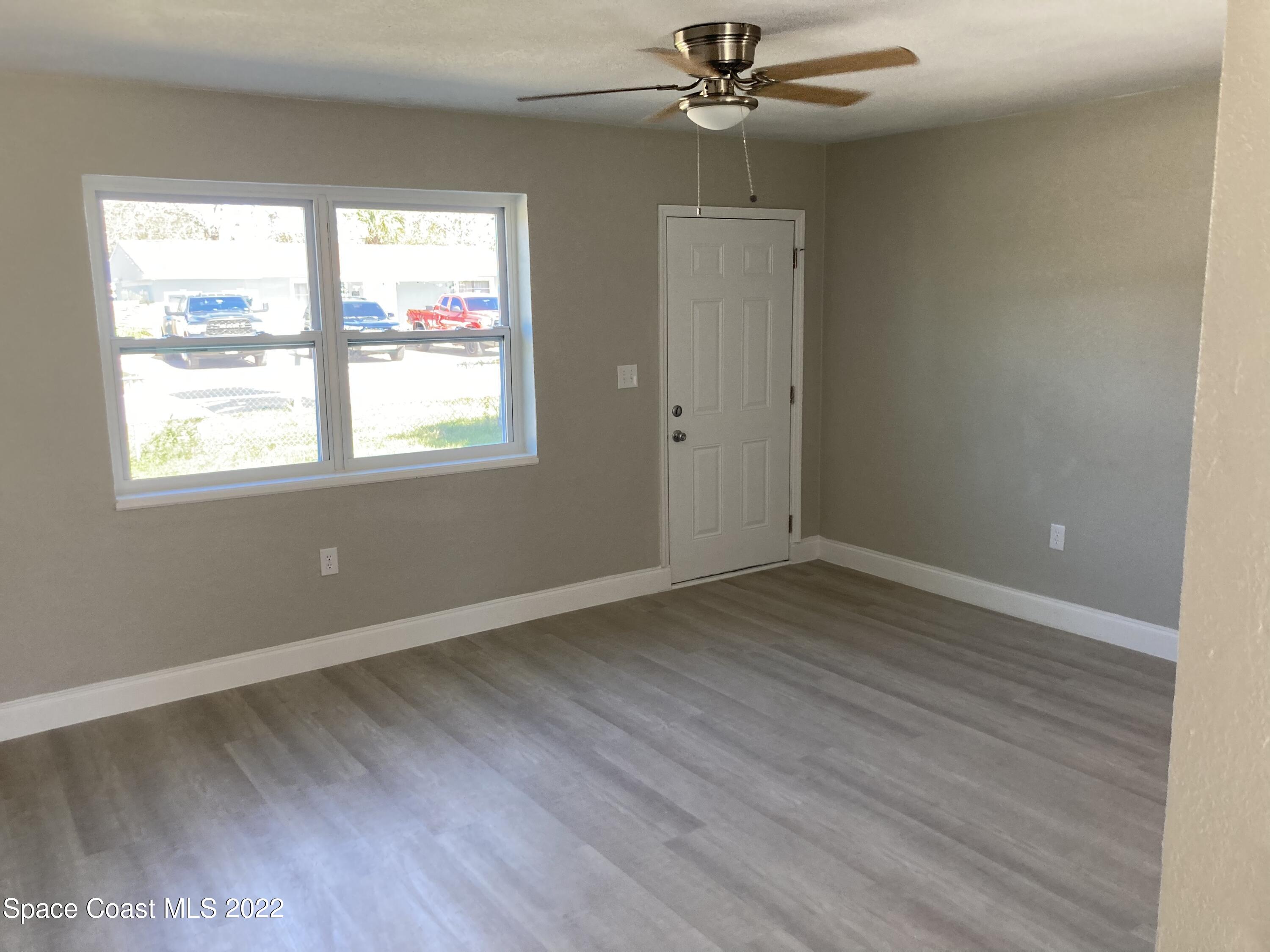1051 Mitchell Street Cocoa, FL 32922 - Photo 4 of 21 an empty room with wooden floor fan and windows