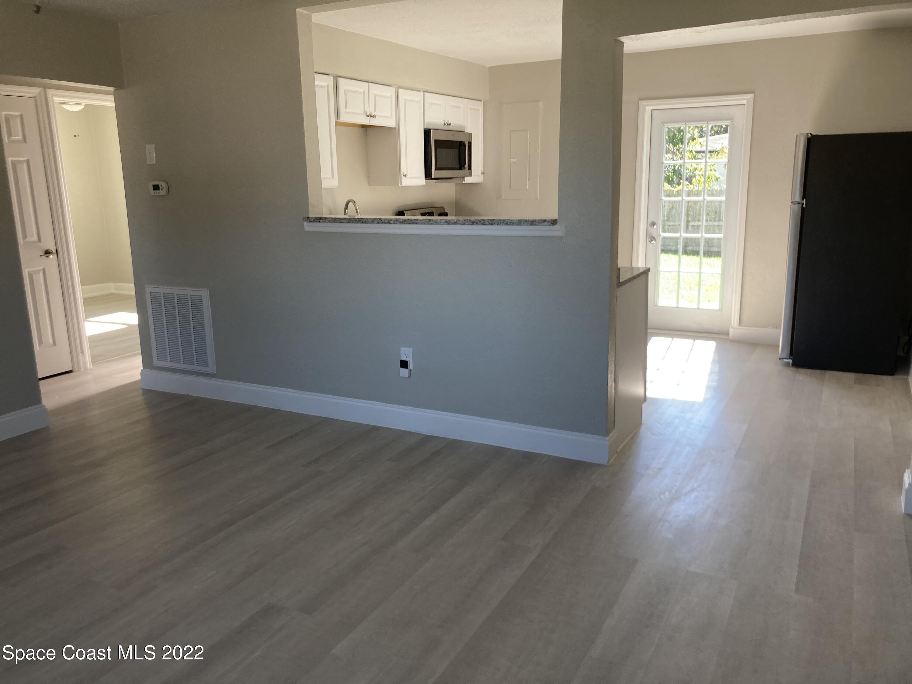 1051 Mitchell Street Cocoa, FL 32922 - Photo 5 of 21 a view of an empty room with wooden floor and a window