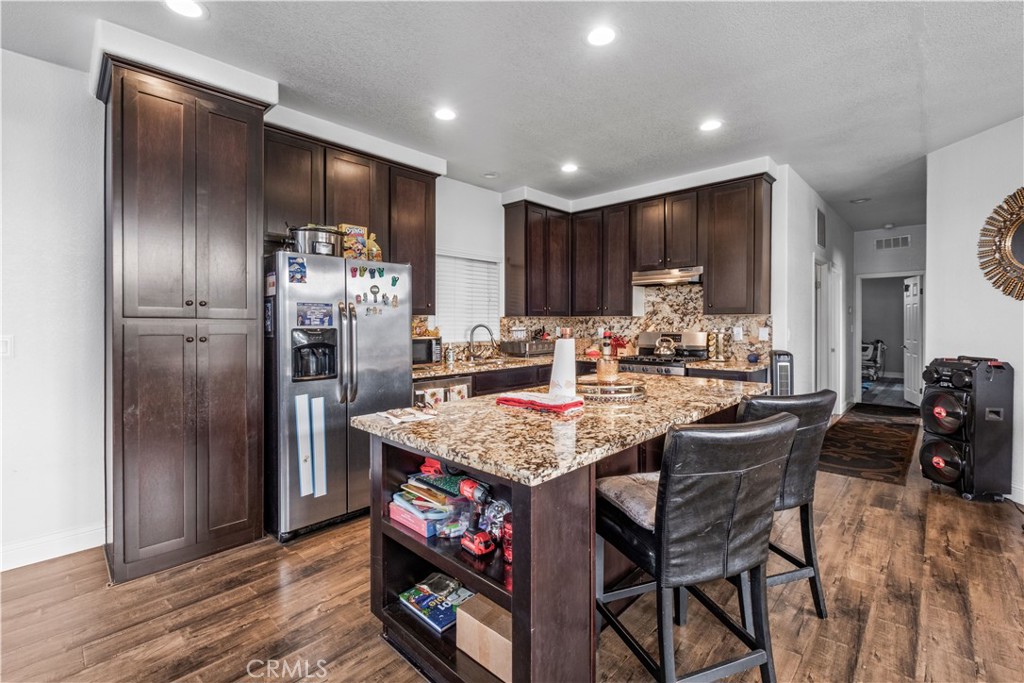 2139 East 4th Street, Unit 84 Ontario, CA 91764 - Photo 11 of 25 a kitchen with stainless steel appliances granite countertop a kitchen island a stove a refrigerator and a dining table