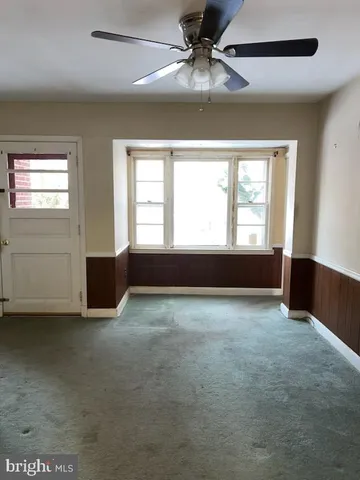 an empty room with chandelier fan and windows