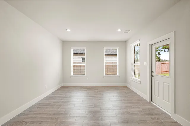 an empty room with wooden floor and windows