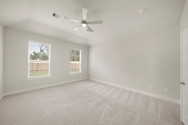 an empty room with chandelier fan and windows