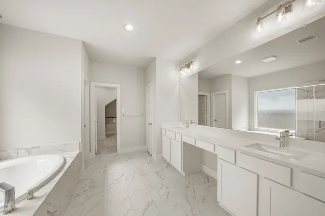 a bathroom with a granite countertop double vanity sink and a bathtub