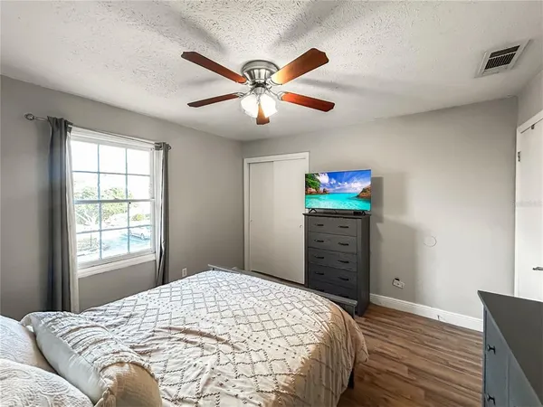 a view of empty room with wooden floor and fan