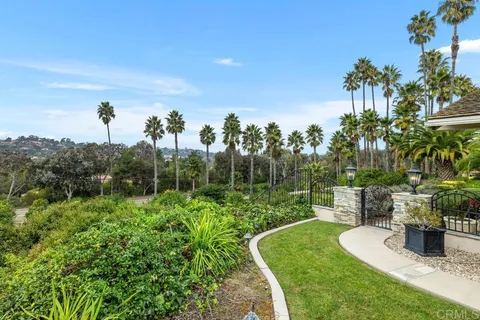 a view of a garden with a bench in front of the house
