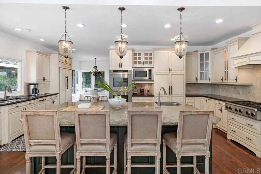 4715 La Noria Rancho Santa Fe, CA 92067 - Photo 3 of 26 a kitchen with a dining table chairs sink and white cabinets
