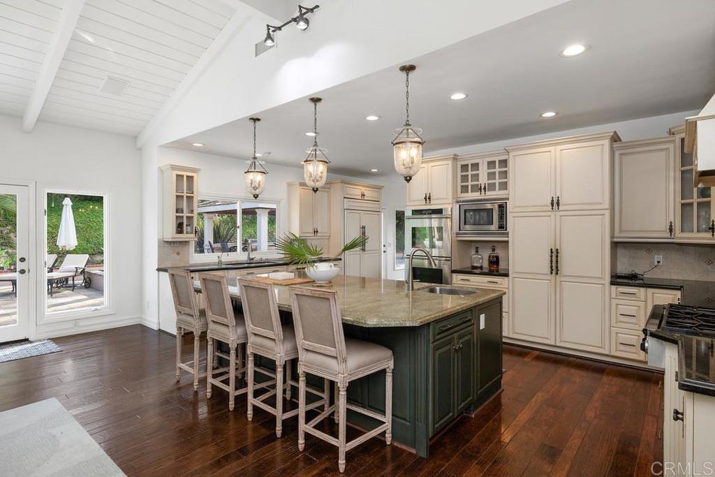 4715 La Noria Rancho Santa Fe, CA 92067 - Photo 5 of 26 a kitchen with stainless steel appliances granite countertop a kitchen island a stove a table and chairs in it