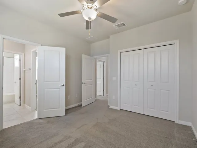 an empty room with a chandelier fan and closet area