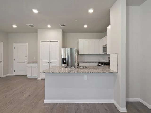 a large kitchen with stainless steel appliances granite countertop a stove a sink and a refrigerator