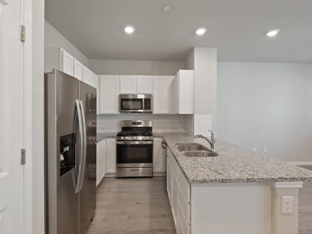 9015 Cattle Baron Path, Unit 2003 Austin, TX 78747 - Photo 10 of 31 a kitchen with granite countertop a refrigerator stove and sink