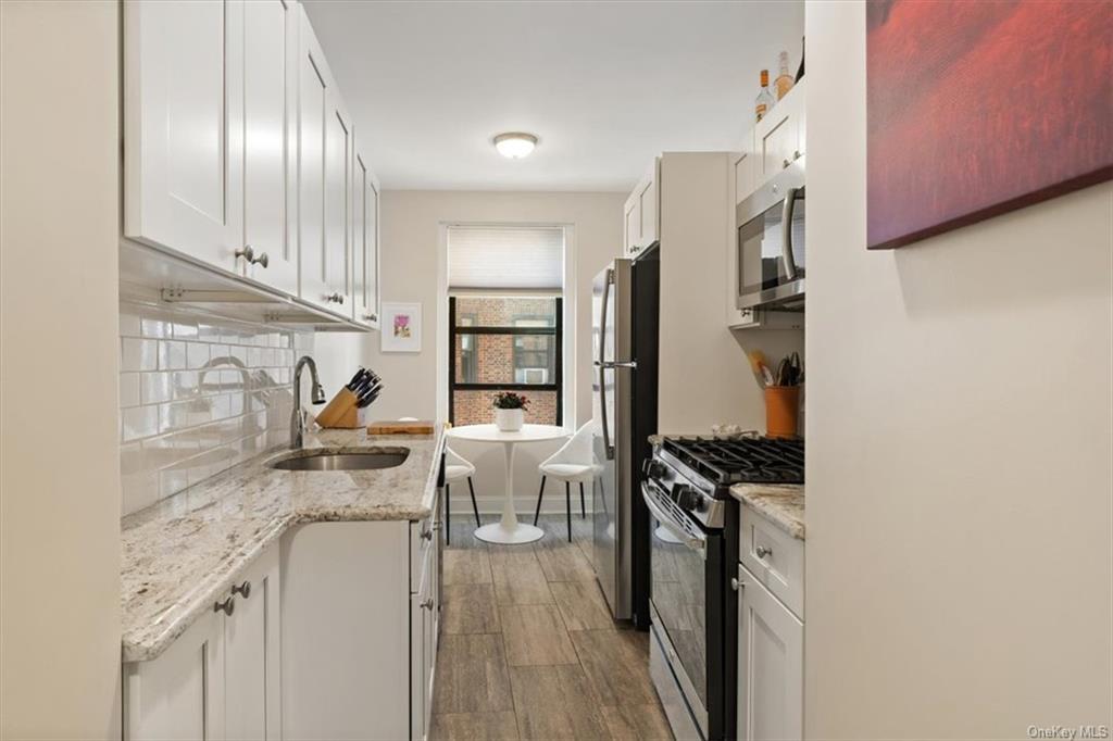 31 Pondfield Road, Unit 46 Bronxville, NY 10708 - Photo 8 of 15 a kitchen with stainless steel appliances granite countertop a refrigerator a stove a sink dishwasher and white countertops with wooden floor