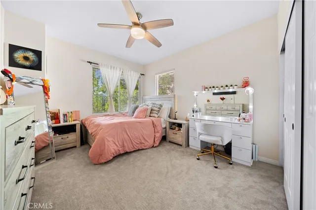 a spacious bedroom with a bed and a flat tv screen on dresser