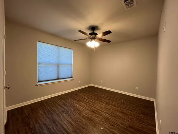 a view of an empty room with a window and a ceiling fan