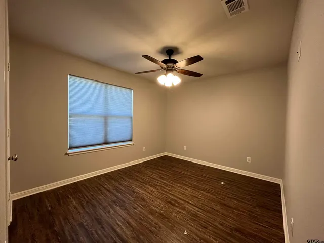a view of an empty room with a window and a ceiling fan