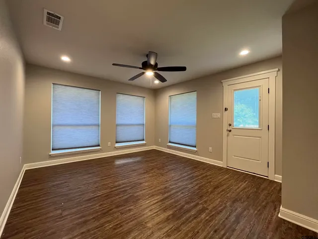 a view of an empty room with wooden floor and a window