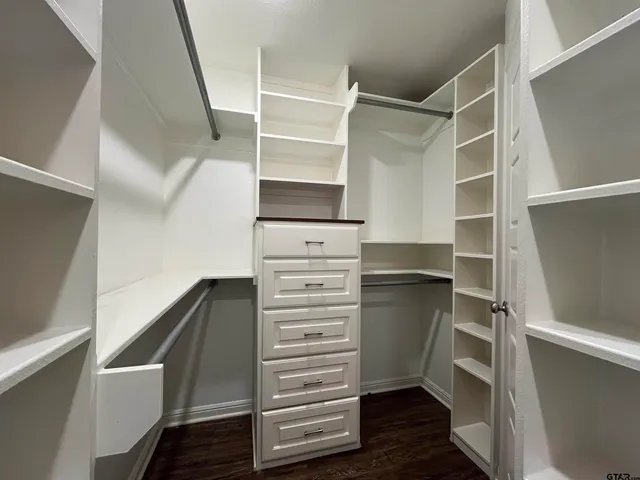 a walk in closet with wooden floor