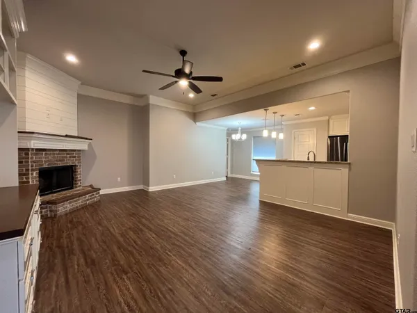 an empty room with wooden floor fireplace and windows