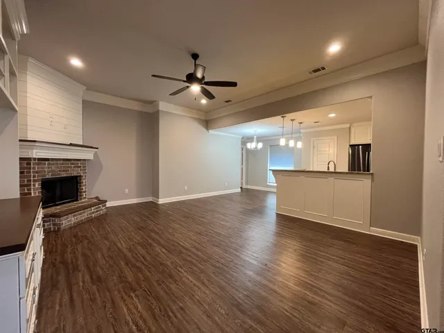an empty room with wooden floor fireplace and windows