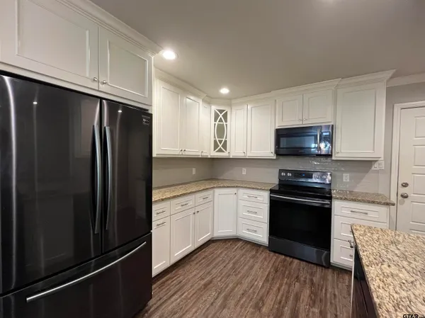 a kitchen with granite countertop a refrigerator stove and microwave