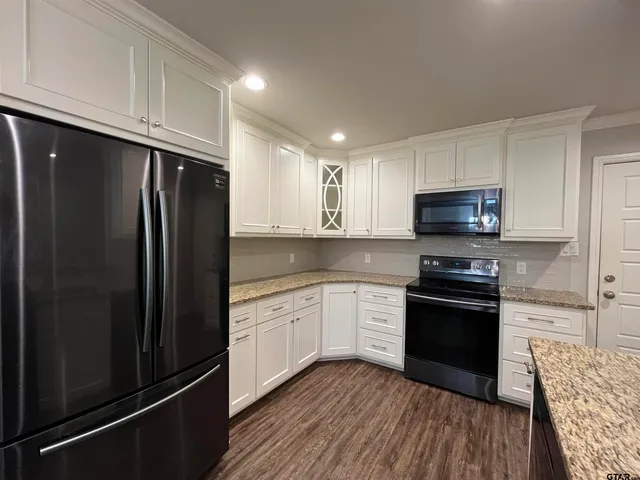 a kitchen with granite countertop a refrigerator stove and microwave