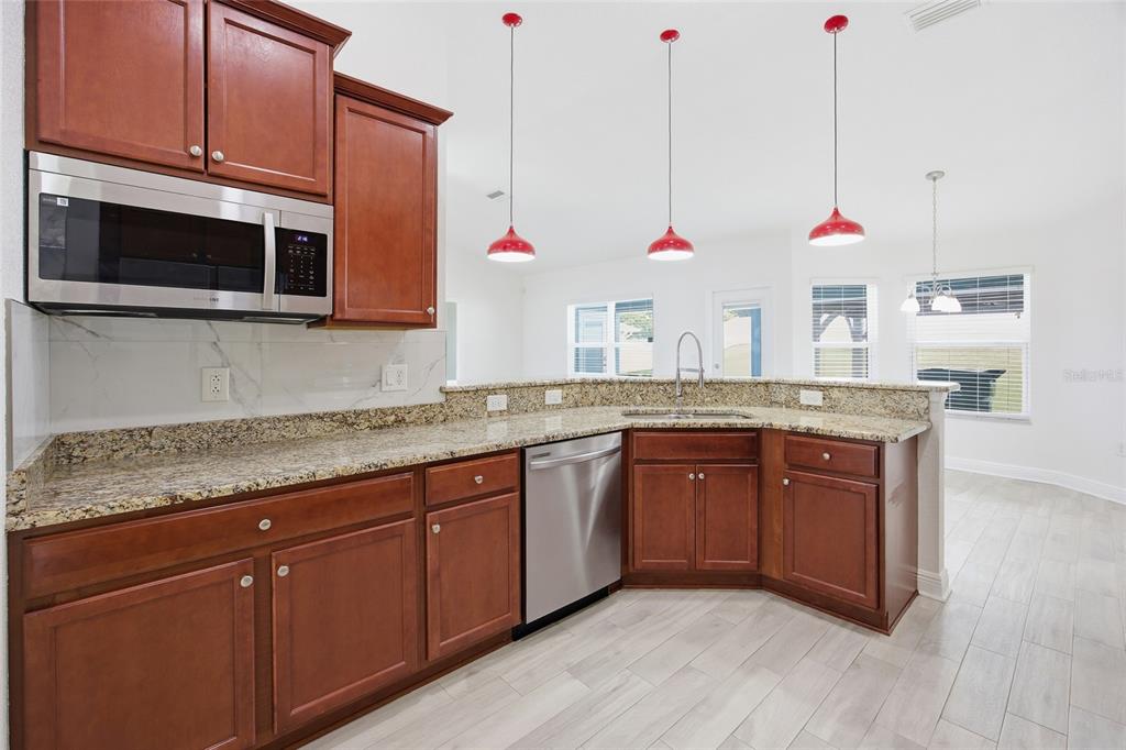 4863 Southwest 63rd Street Ocala, FL 34474 - Photo 14 of 41 a kitchen with stainless steel appliances granite countertop a sink a microwave a stove and a wooden cabinets