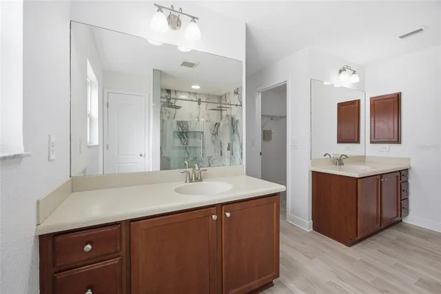 a bathroom with a sink vanity granite tub and a mirror
