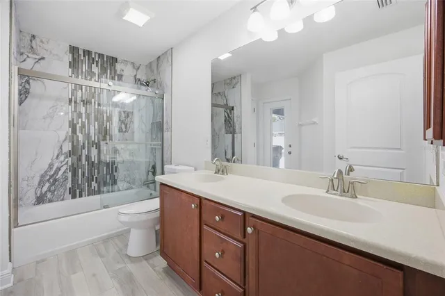 a bathroom with a double vanity sink toilet mirror and shower