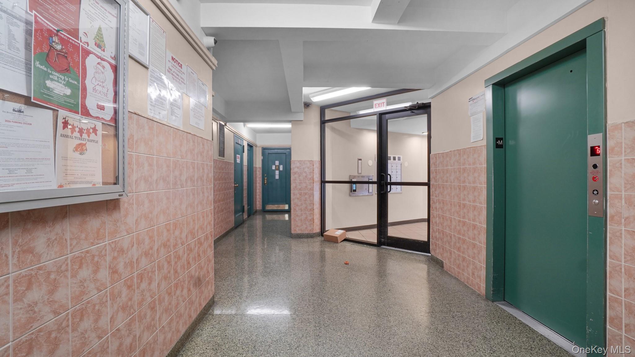 2220 East Tremont Avenue, Unit 7F Bronx, NY 10462 - Photo 12 of 13 Corridor featuring tile walls, elevator, a wainscoted wall, and speckled floor