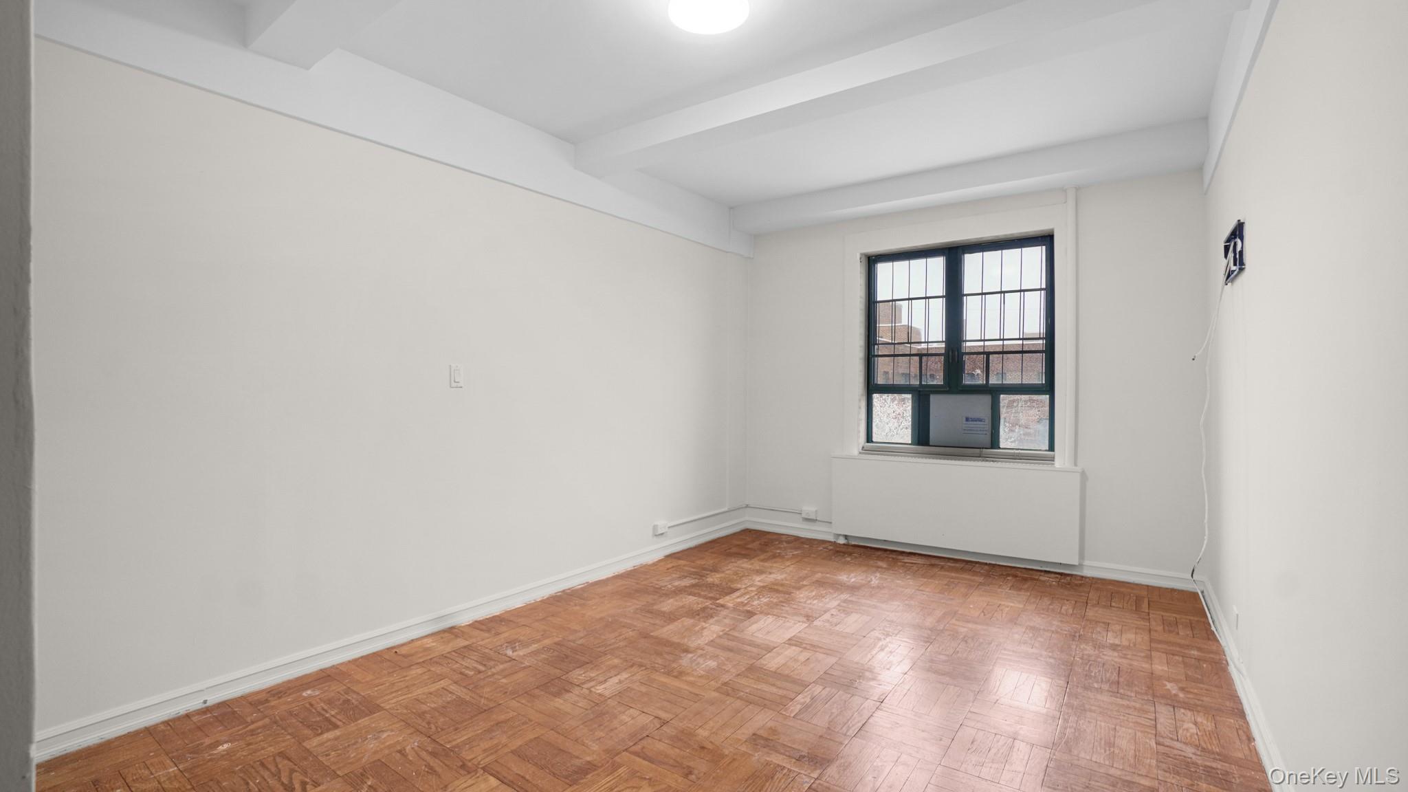 2220 East Tremont Avenue, Unit 7F Bronx, NY 10462 - Photo 6 of 13 Empty room with radiator and beamed ceiling