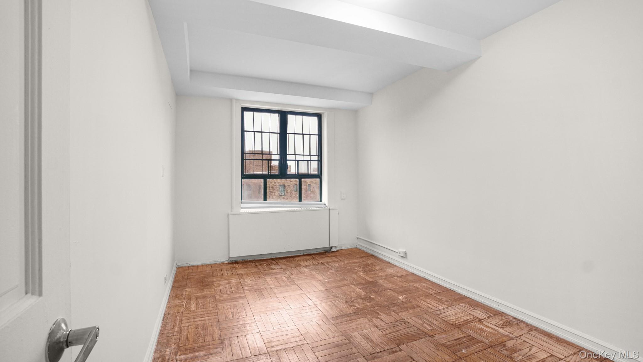 2220 East Tremont Avenue, Unit 7F Bronx, NY 10462 - Photo 9 of 13 Empty room with radiator and baseboards