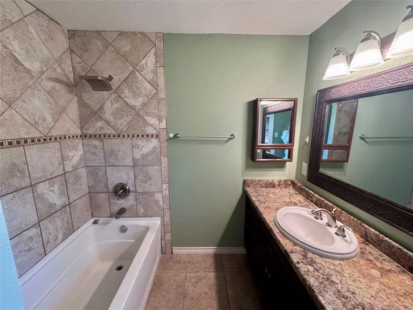 a bathroom with a granite countertop bathtub sink vanity mirror and toilet