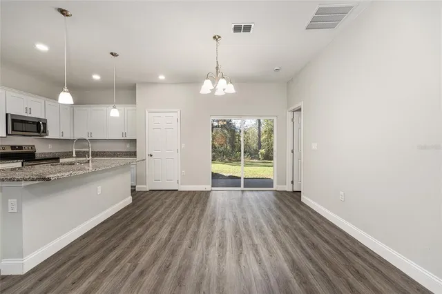 a large kitchen with kitchen island a sink dishwasher a stove and white cabinets with wooden floor