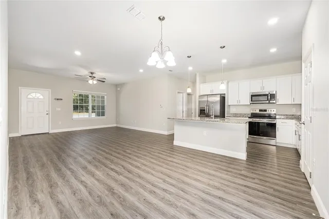 a view of kitchen with granite countertop cabinets large counter top and stainless steel appliances