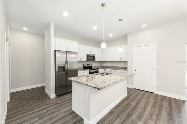 a large kitchen with a center island wooden floor stainless steel appliances and windows