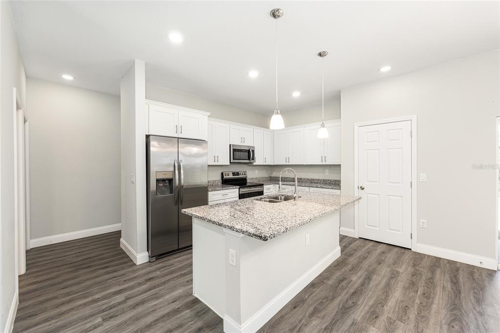 5998 Southwest 154th Street Road Ocala, FL 34473 - Photo 14 of 38 a large kitchen with a center island wooden floor stainless steel appliances and windows
