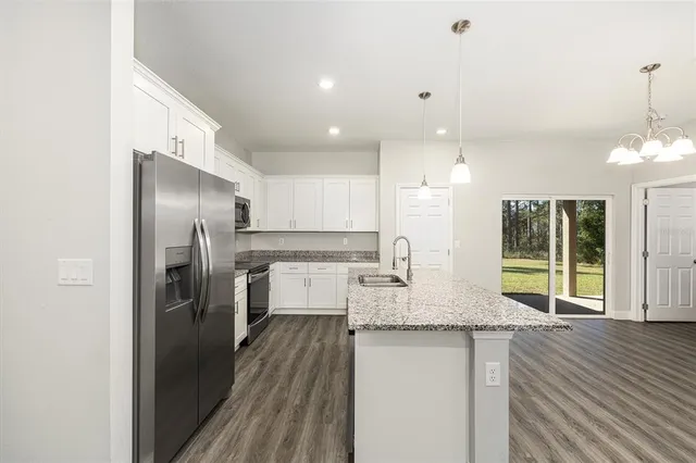 a kitchen with kitchen island granite countertop a refrigerator a oven a sink counter space and chairs