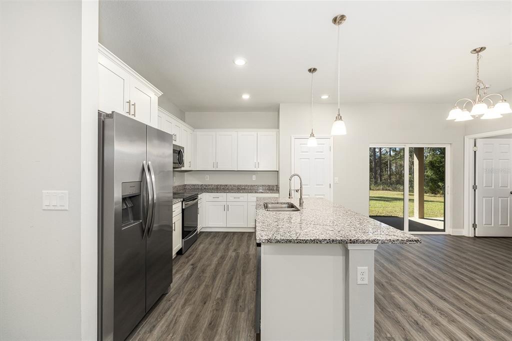 5998 Southwest 154th Street Road Ocala, FL 34473 - Photo 15 of 38 a kitchen with kitchen island granite countertop a refrigerator a oven a sink counter space and chairs