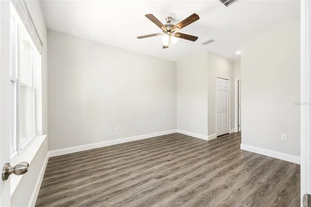 an empty room with wooden floor and windows