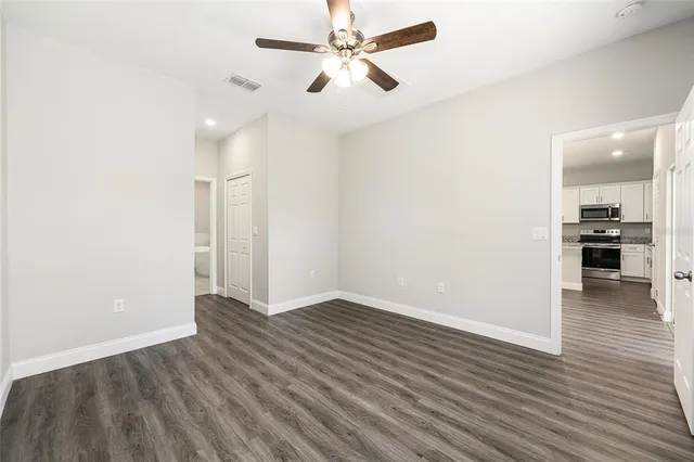 an empty room with wooden floor and ceiling fan