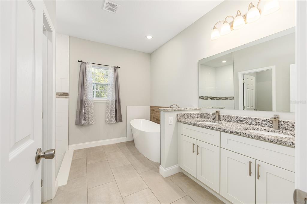 5998 Southwest 154th Street Road Ocala, FL 34473 - Photo 21 of 38 a spacious bathroom with a granite countertop sink a toilet and a mirror